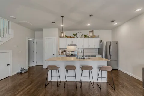a kitchen with kitchen island wooden floors and refrigerator