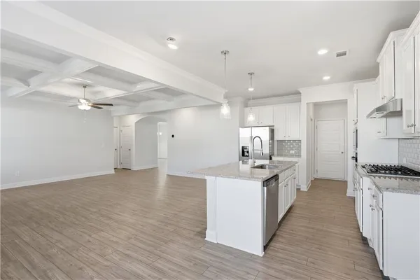 a kitchen with stainless steel appliances a stove top oven a sink a refrigerator and white cabinets