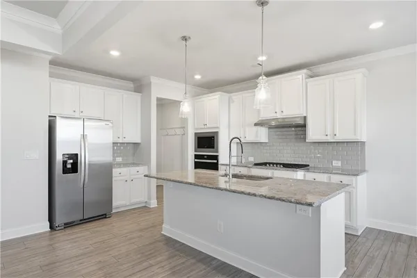 a kitchen with stainless steel appliances granite countertop a refrigerator a sink a stove and oven with wooden floor