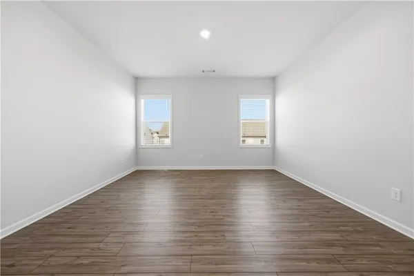 a view of an empty room with wooden floor and window