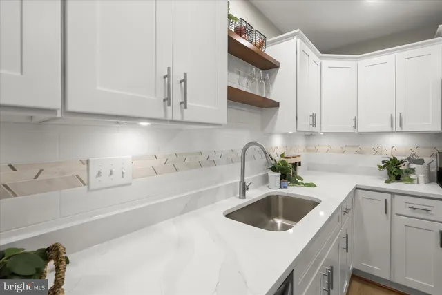 a kitchen with stainless steel appliances a sink a stove and white cabinets with wooden floor