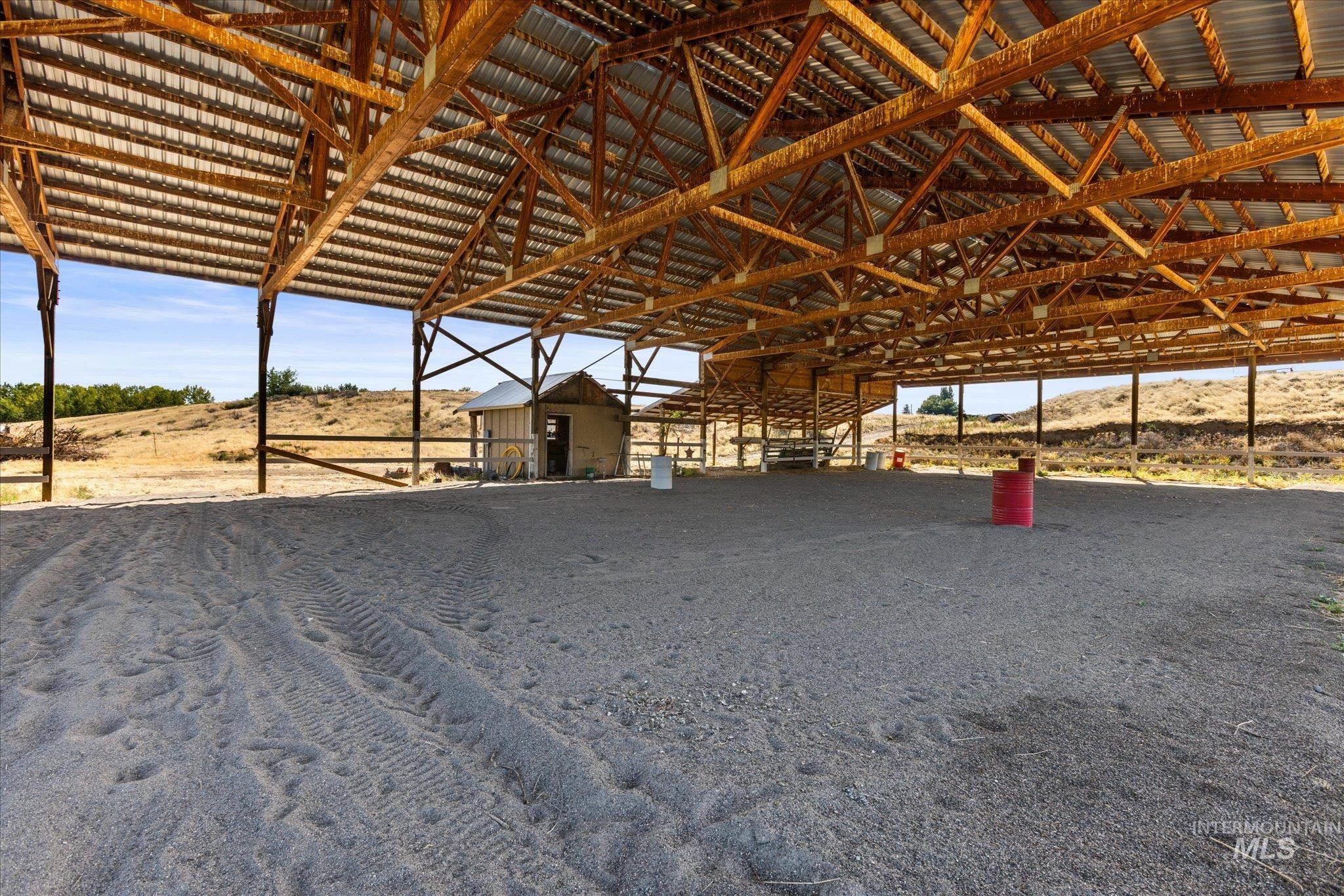 1030 Desert Glen Road Adrian, OR 97901 - Photo 39 of 50 Expansive covered arena featuring a high-pitched metal roof and exposed wooden beam framework