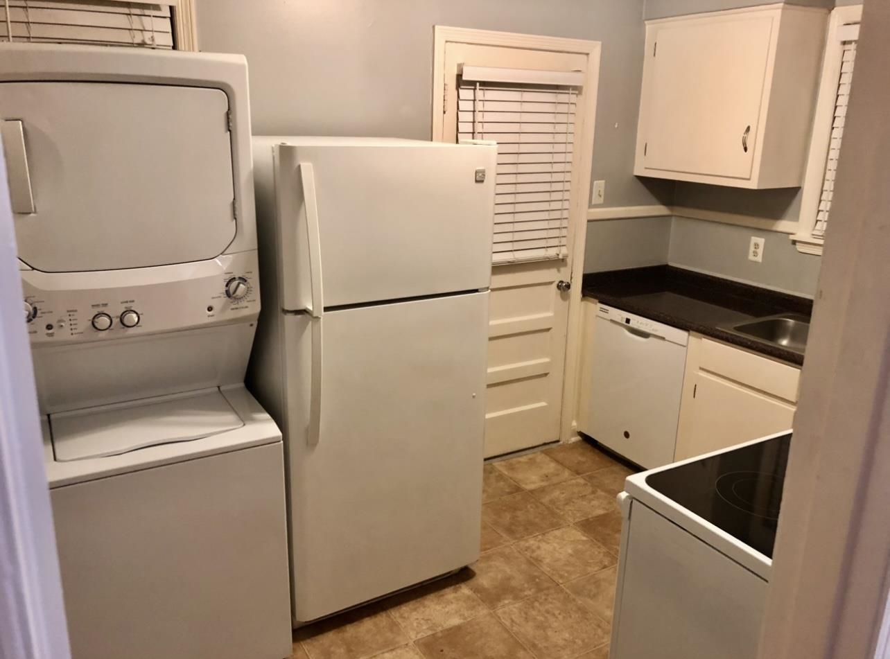 505 High Point Terrace Memphis, TN 38122 - Photo 20 of 29 Kitchen with white appliances, stacked washer and clothes dryer, dark countertops, white cabinetry, and a sink