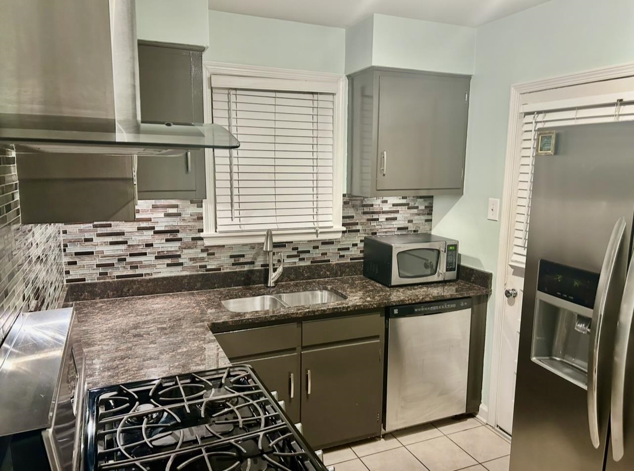 505 High Point Terrace Memphis, TN 38122 - Photo 9 of 29 Kitchen with gray cabinets, stainless steel appliances, backsplash, a sink, and wall chimney range hood