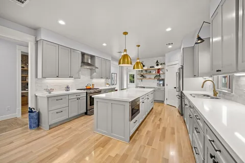 a kitchen with kitchen island granite countertop wooden floors and white cabinets