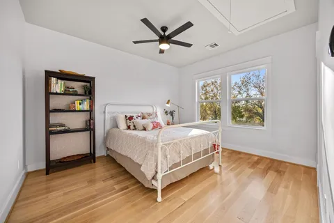 a view of empty room with wooden floor and fan