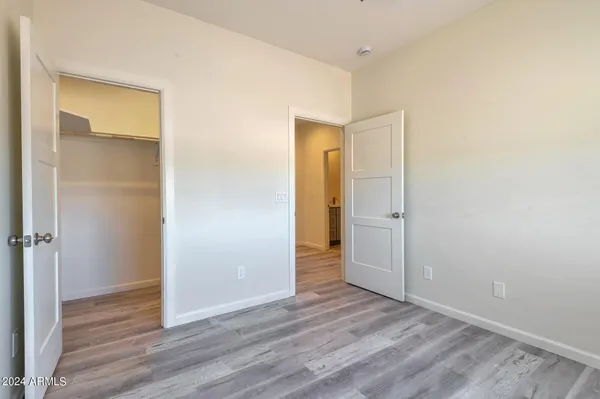 a view of an empty room with wooden floor and closet