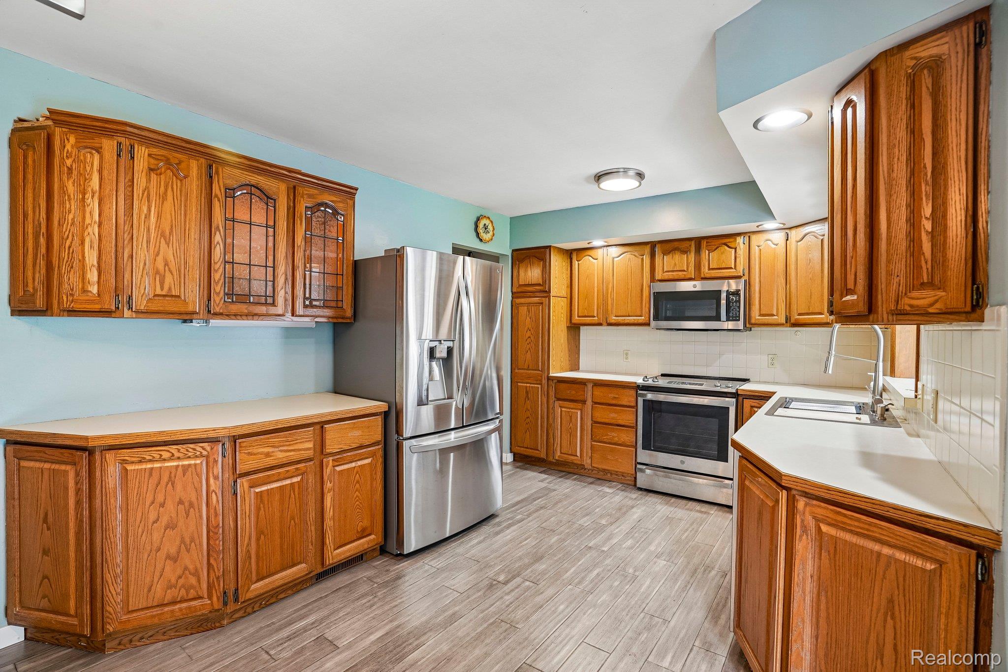 3981 South State Road Durand, MI 48429 - Photo 8 of 33 Wood-finish cabinetry, stainless steel appliances, light-toned countertops, and wood-finish flooring