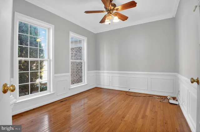 an empty room with wooden floor closet and windows