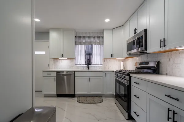 a kitchen with stainless steel appliances granite countertop a sink and dishwasher a stove top oven with white cabinets