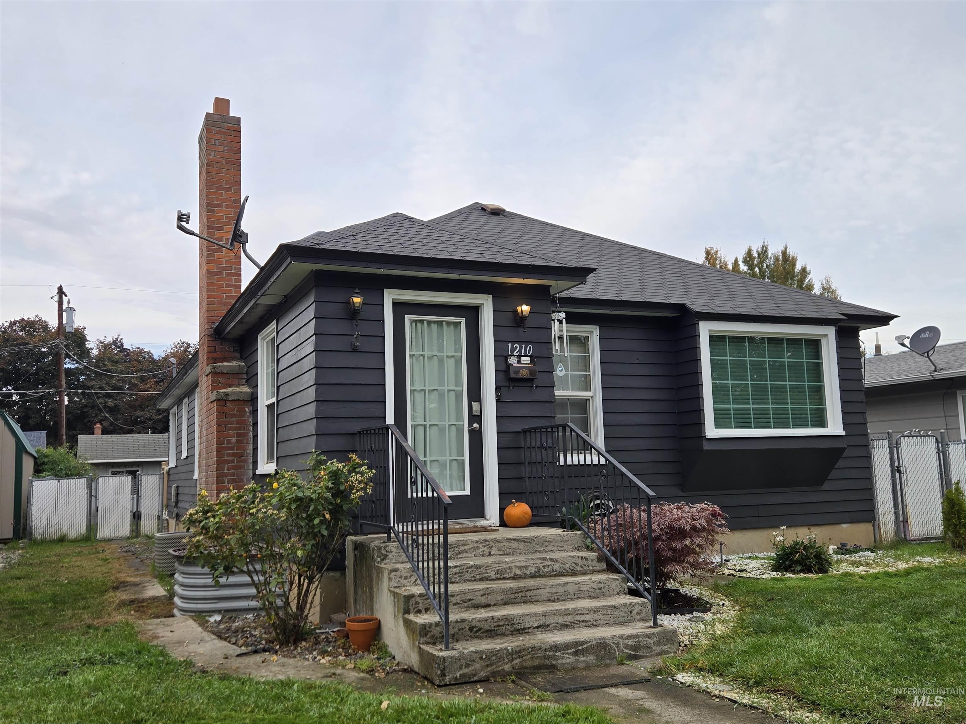 View of front facade with a gate and a chimney