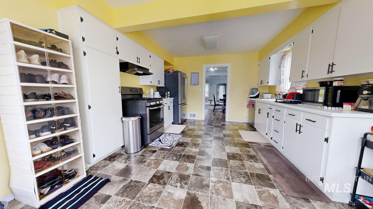 1210 10th Street Lewiston, ID 83501 - Photo 5 of 25 Kitchen with appliances with stainless steel finishes, white cabinetry, and stone finish floors