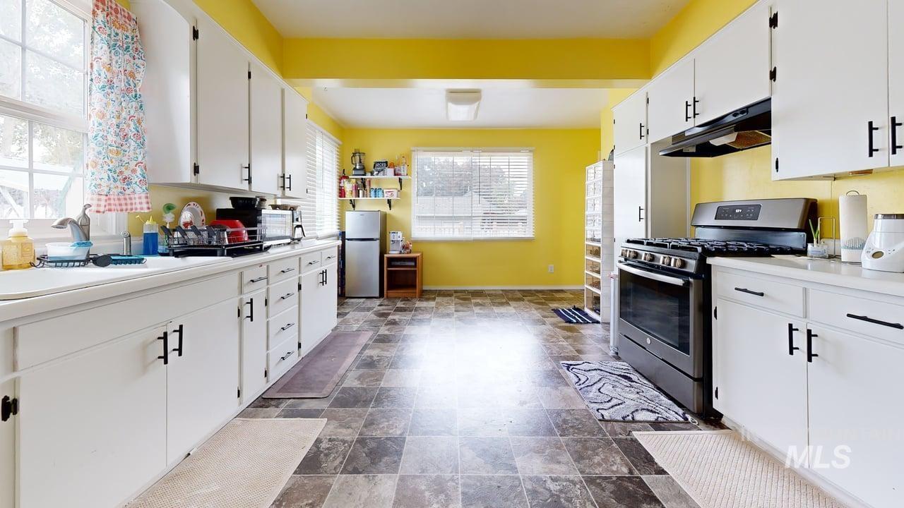 1210 10th Street Lewiston, ID 83501 - Photo 6 of 25 Kitchen featuring stainless steel appliances, white cabinetry, stone finish floors, and under cabinet range hood