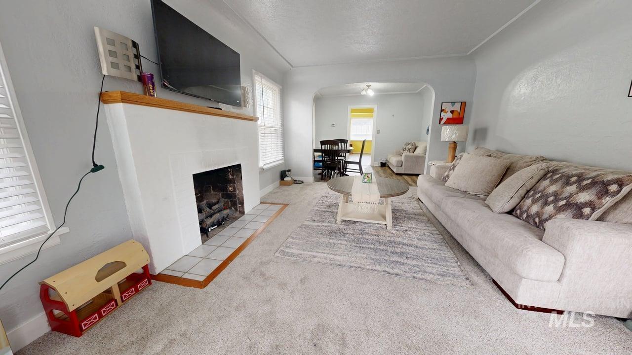 1210 10th Street Lewiston, ID 83501 - Photo 8 of 25 Living room featuring carpet flooring, arched walkways, a tiled fireplace, a textured ceiling, and tile patterned floors