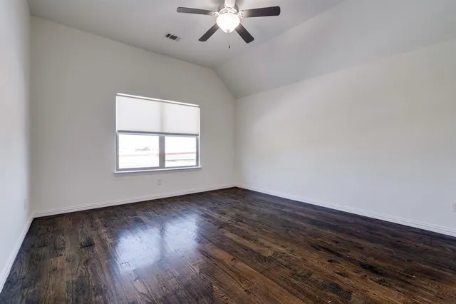 an empty room with wooden floor chandelier fan and windows