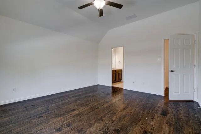 an empty room with wooden floor chandelier fan and windows