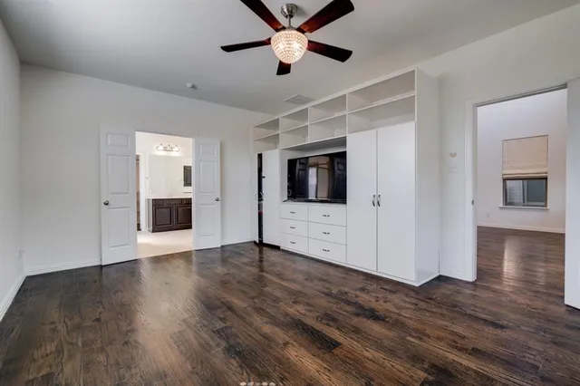 a view of an empty room with wooden floor and a kitchen