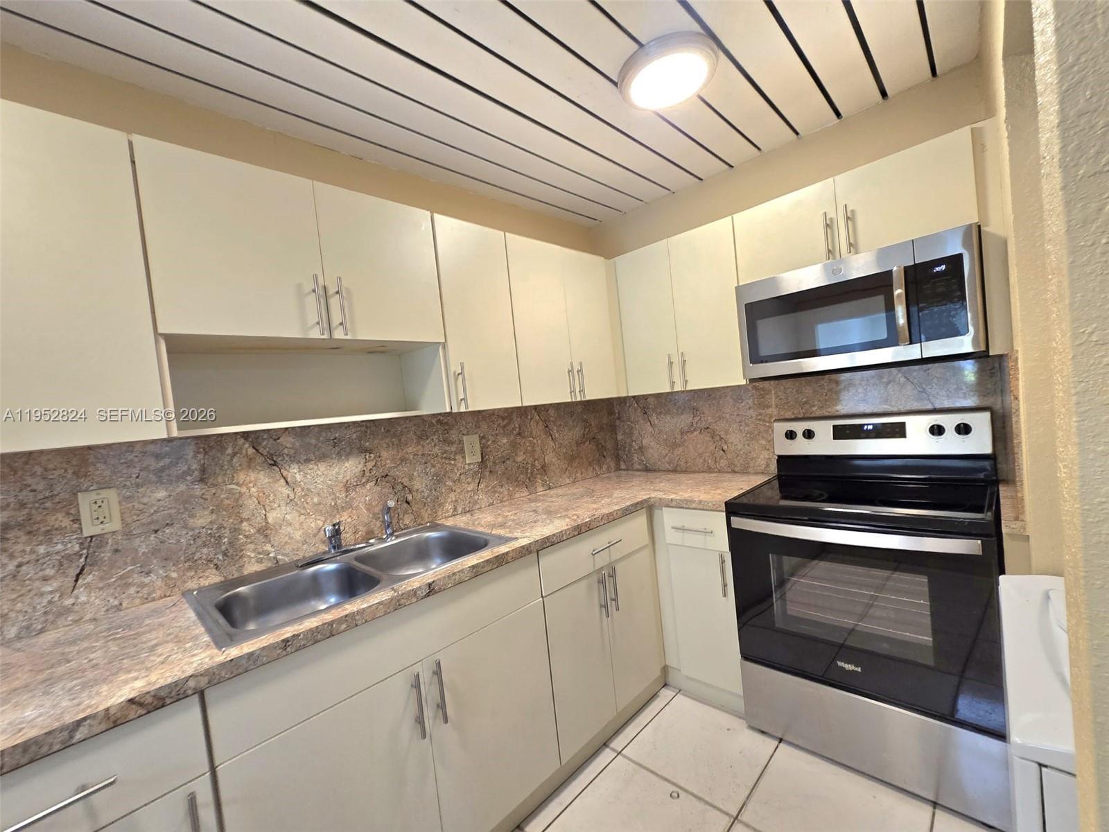10090 Northwest 80th Court, Unit 1155 Hialeah Gardens, FL 33016 - Photo 3 of 19 a kitchen with a sink and cabinets