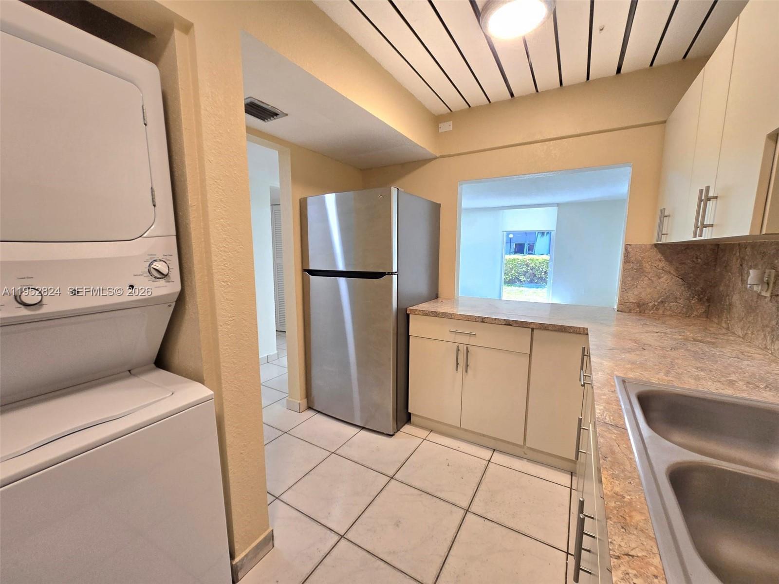 10090 Northwest 80th Court, Unit 1155 Hialeah Gardens, FL 33016 - Photo 4 of 19 a kitchen with a refrigerator sink washer and dryer