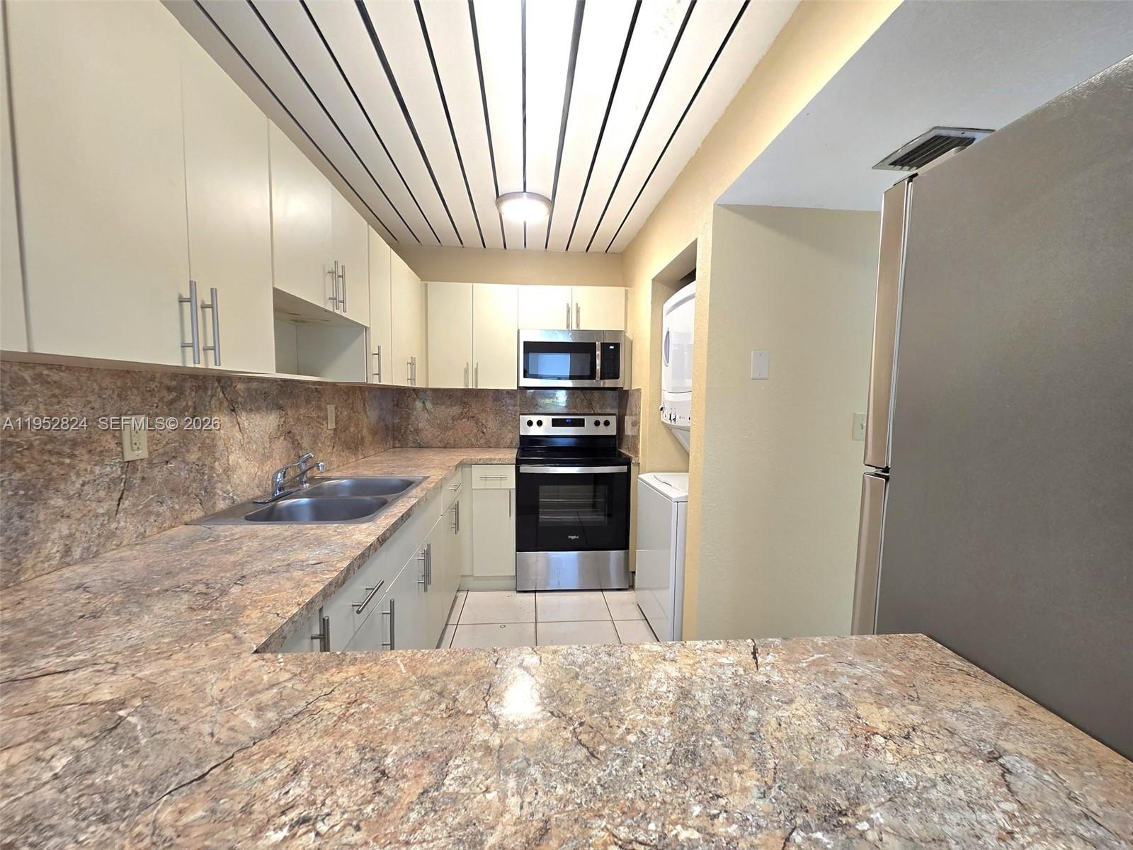 10090 Northwest 80th Court, Unit 1155 Hialeah Gardens, FL 33016 - Photo 6 of 19 a kitchen with granite countertop a refrigerator and a stove top oven