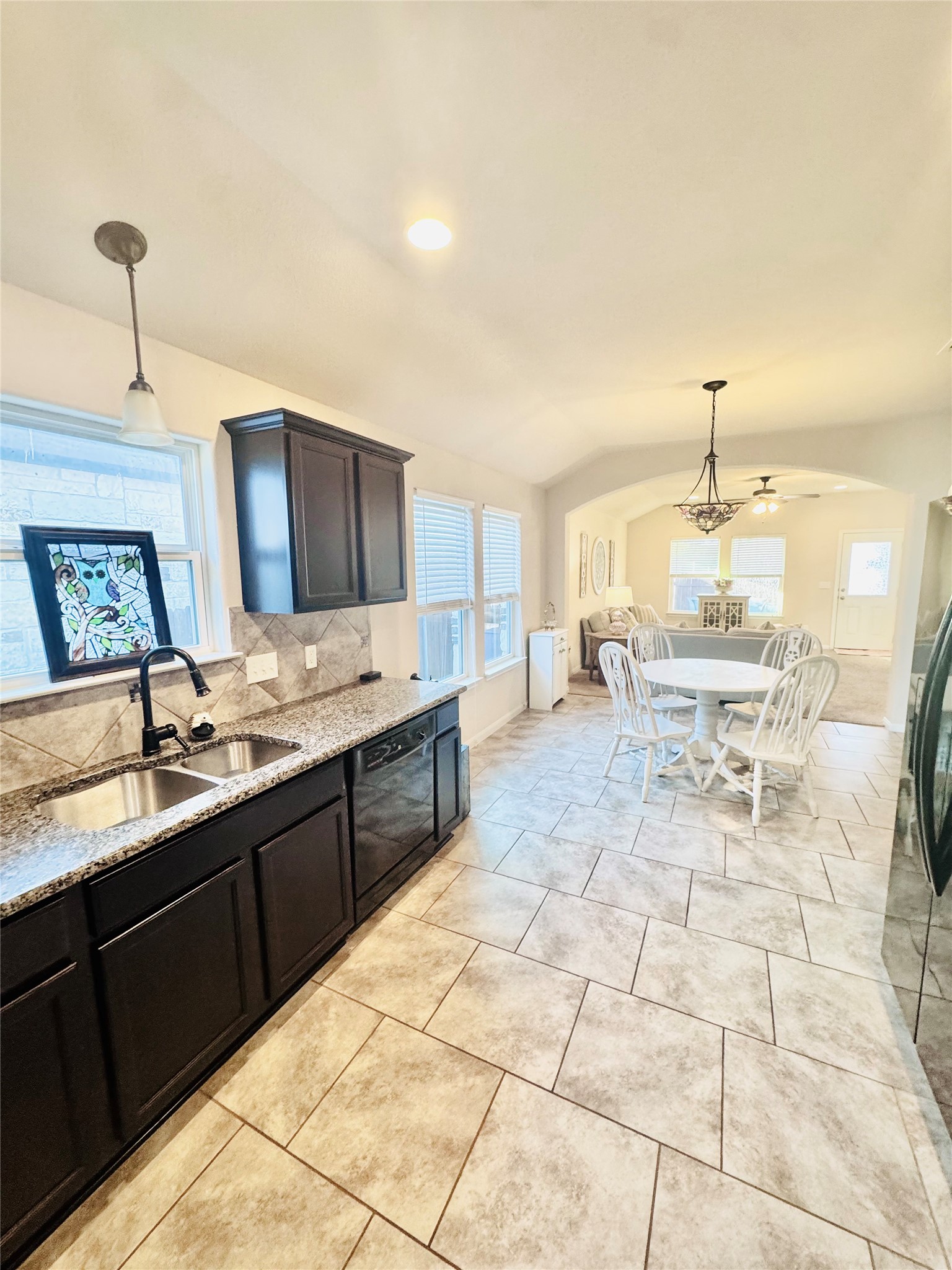 413 Gettysburg Loop Elgin, TX 78621 - Photo 11 of 32 Kitchen with decorative light fixtures, light stone counters, vaulted ceiling, arched walkways, and plenty of natural light