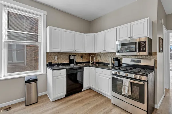 a kitchen with stainless steel appliances granite countertop a stove a sink and a microwave