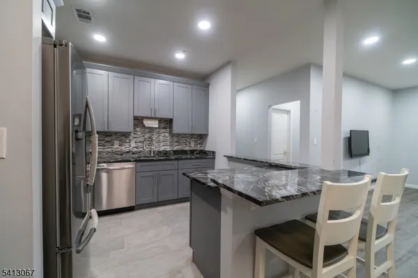 a kitchen with kitchen island granite countertop wooden cabinets and a refrigerator