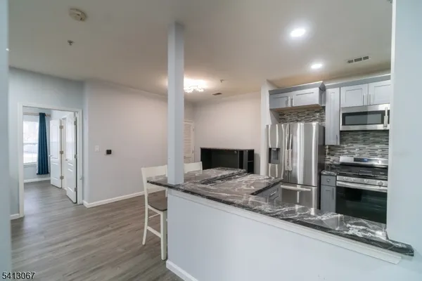 a kitchen with stainless steel appliances granite countertop a refrigerator and a stove top oven