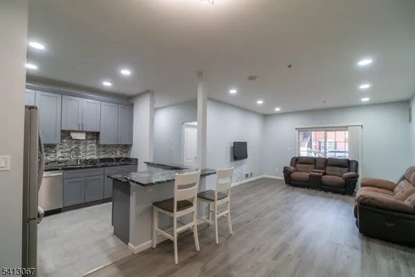 a living room with stainless steel appliances kitchen island granite countertop furniture a refrigerator a sink a stove a dining table and chairs
