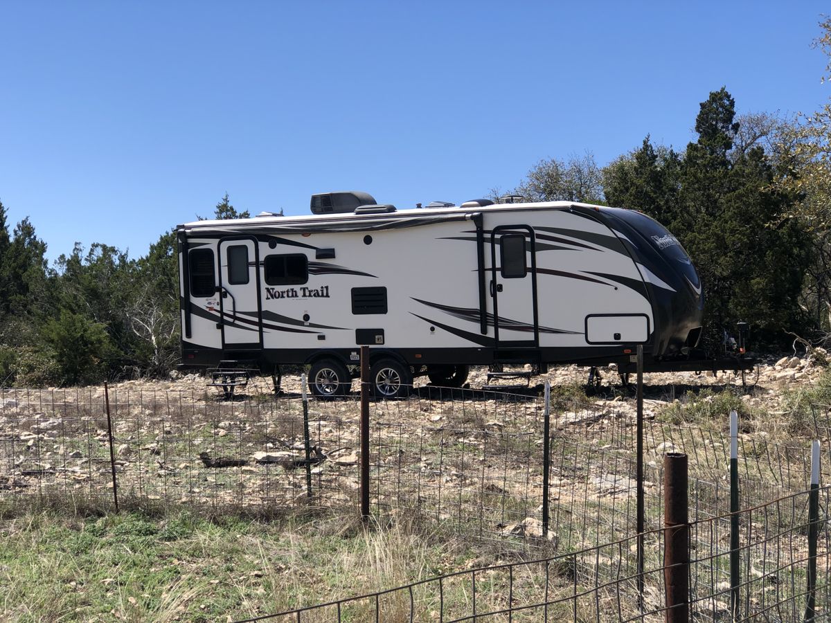 635 County Road 635 Rocksprings, TX 78880 - Photo 11 of 31 A travel trailer rests within a natural landscape, offering convenient accommodation amidst the outdoors.
