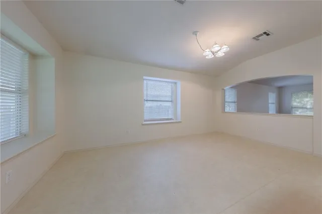 an empty room with windows and chandelier fan