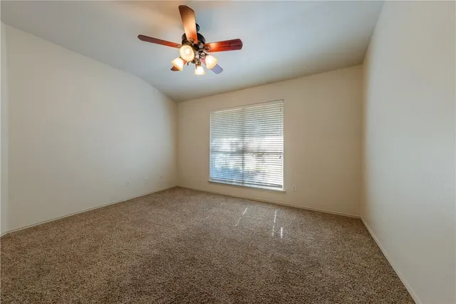 an empty room with chandelier fan and windows