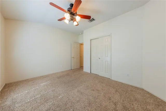 an empty room with a chandelier fan and closet area