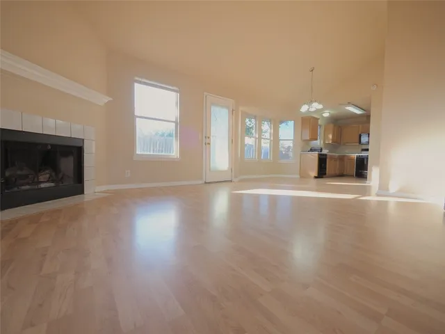 an empty room with wooden floor fireplace and windows
