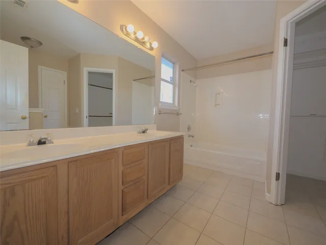 a bathroom with a double vanity sink a mirror and a bathtub