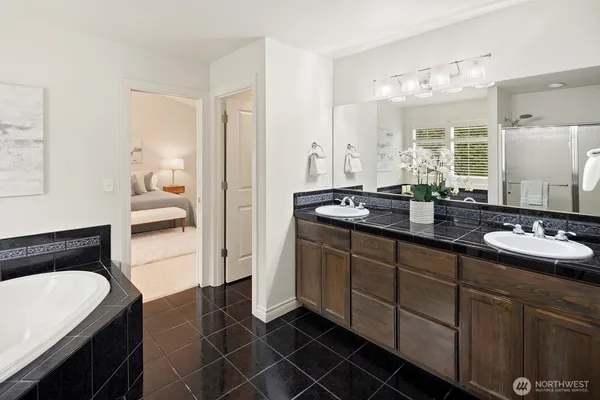 a en suite bathroom with a double vanity sink a mirror and a bathtub