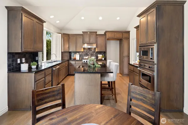 a kitchen with stainless steel appliances kitchen island granite countertop a refrigerator and a stove top oven