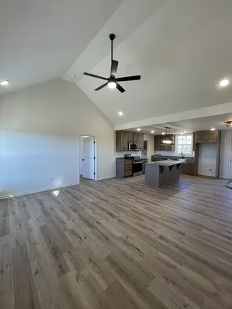 an empty room with wooden floor ceiling fan and windows