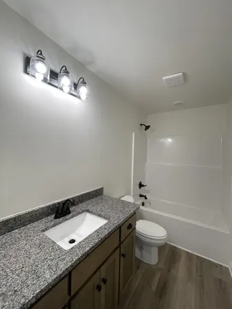 a bathroom with a granite countertop sink a toilet and shower