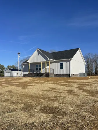 a big house with wooden fence and trees in the background