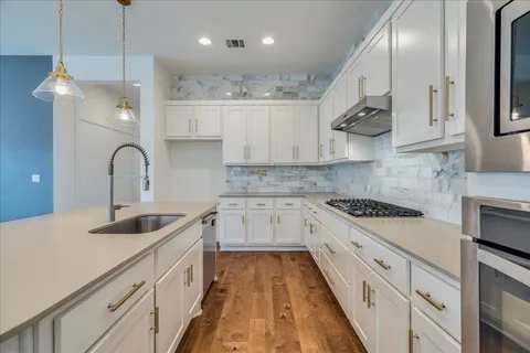 a kitchen with kitchen island granite countertop a sink stainless steel appliances and cabinets