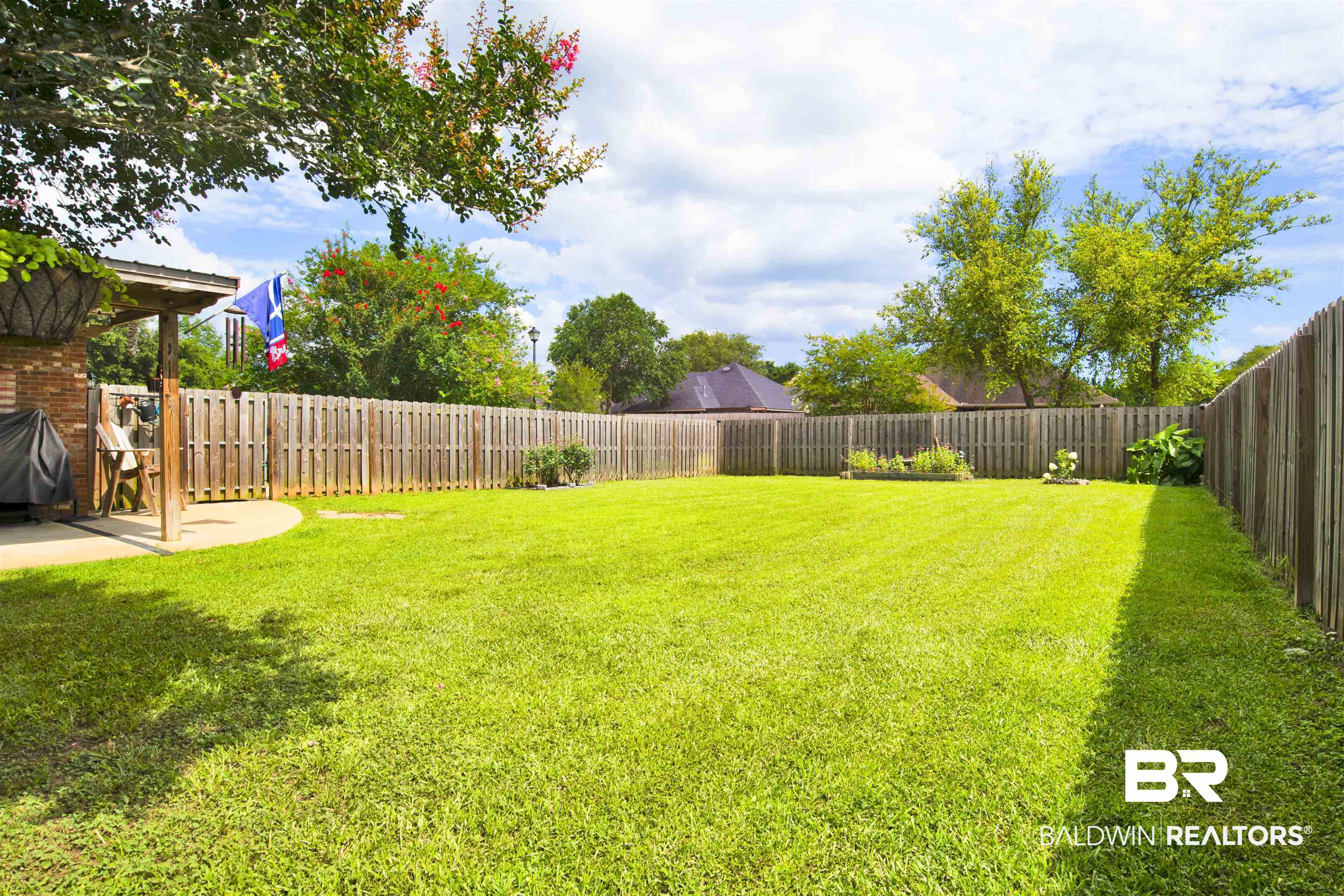 10368 Gayfer Rd Extension Fairhope, AL 36532 - Photo 37 of 43 Expansive backyard featuring a lush lawn, privacy fencing, and a covered patio area with a concrete slab