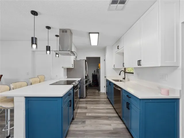 a large kitchen with stainless steel appliances kitchen island a sink stove and cabinets