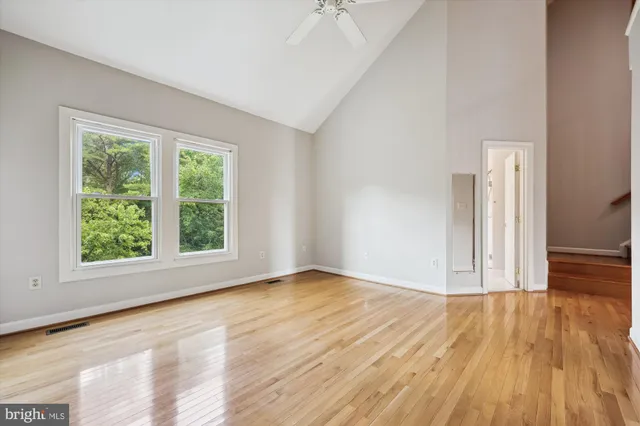 an empty room with wooden floor and windows