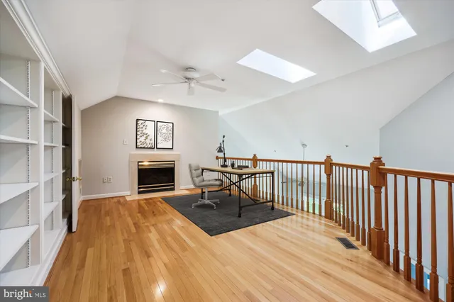 a view of a livingroom with fireplace a ceiling fan and wooden floor