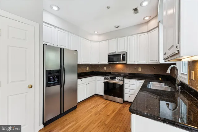 a kitchen with granite countertop a refrigerator stove and sink