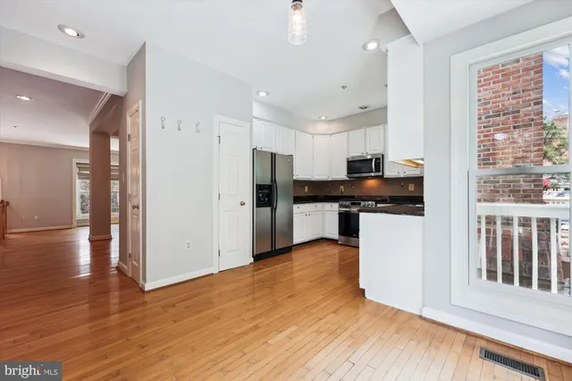 a kitchen with stainless steel appliances a refrigerator and wooden floor