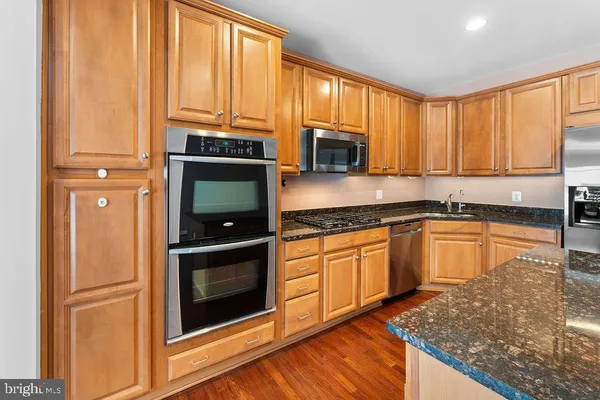 a kitchen with stainless steel appliances granite countertop a refrigerator a stove a sink and a microwave