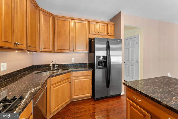a kitchen with granite countertop stainless steel appliances a refrigerator a sink and cabinets