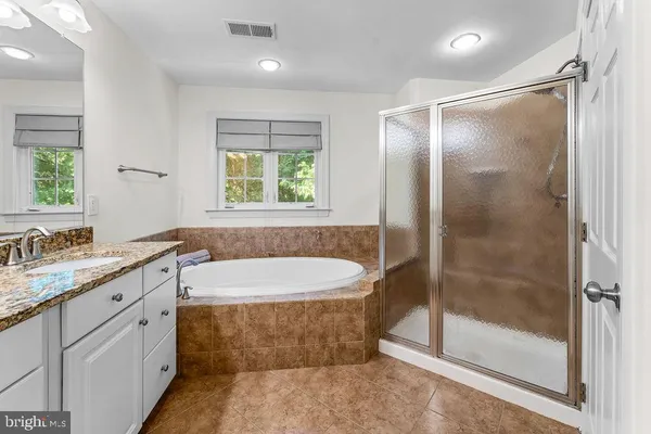 a bathroom with a granite countertop bathtub shower sink and mirror